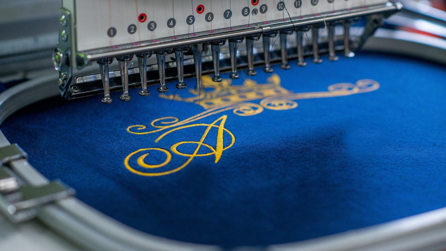 Embroidery machine in action with blue fabric and yellow design