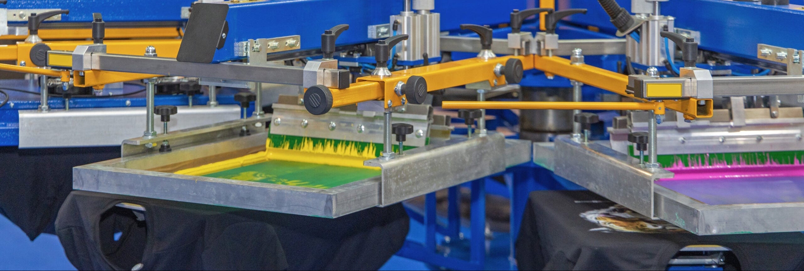 Automated screen printing press with black t-shirts being printed