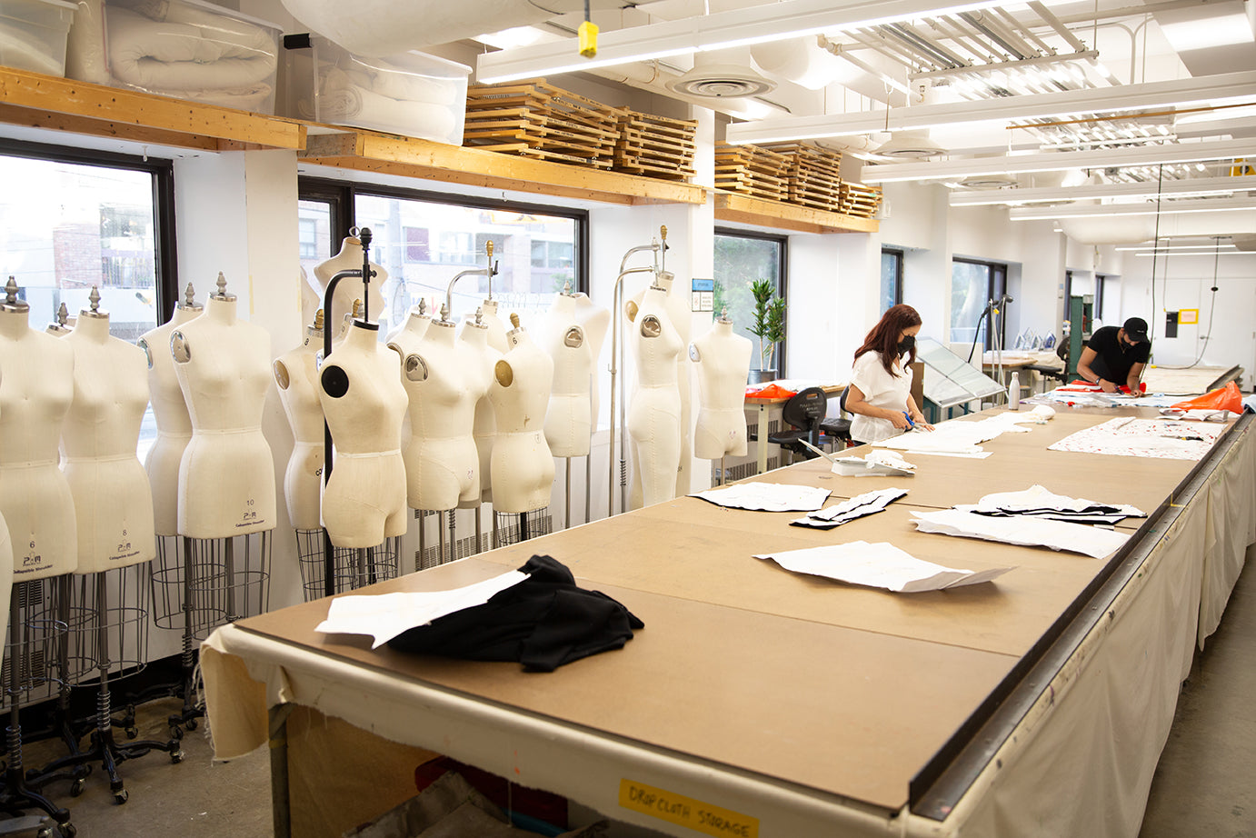 Cut & sew studio with mannequins and tables, with 2 workers