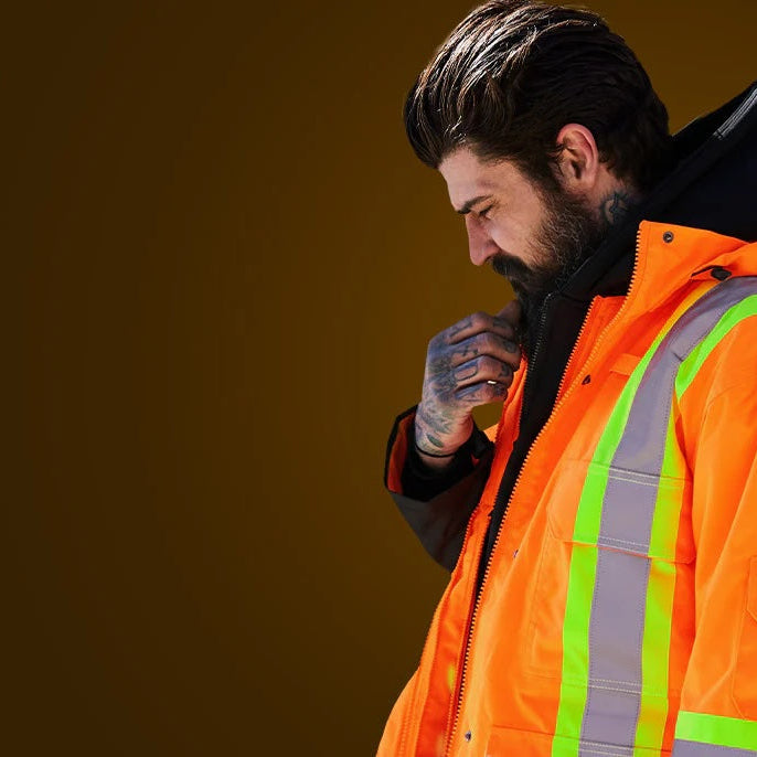 Man wearing an orange safety jacket with reflective stripes on a brown background