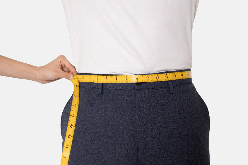 Person measuring waist with yellow measuring tape on white background